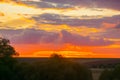 Natural sunset over a field or meadow. Bright dramatic sky and dark earth. Countryside landscape under a picturesque colorful sky Royalty Free Stock Photo