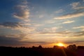 Natural sunset sunrise over field or meadow. Bright dramatic sky and dark ground. countryside landscape under scenic colorful sky Royalty Free Stock Photo