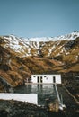 Natural swimming pool Seljavallalaug in iceland with man in water and snowy weather and mountains all around. Sunny