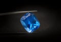 Natural Swiss Blue Topaz Cushion Shape Gems Stone oval cut beautiful.Holding a blue stone by tweezers Royalty Free Stock Photo