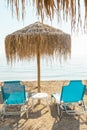 Natural thatched beach umbrella with two blue sunbeds, tropical style parasol Royalty Free Stock Photo