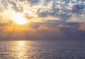 Natural tropical sundown on the sea with dramatic clouds. Sunset sky backlit by the sun over the ocean. Colorful rays reflected in