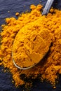 Natural turmeric powder on a dark stone background