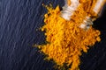 Natural turmeric powder on a dark stone background