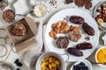 Natural useful sweets from dates, nuts, honey and raisins on a white plate. These ingredients are next on the table