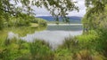 Natural view of calm lake and green field in Loch, Scotland