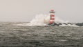 Natural view of strong waves on a rocky coast and a lighthouse on a sunny day