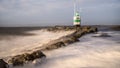 Natural view of strong waves on a rocky coast and a lighthouse on a sunny day