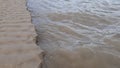 Water flows and scour the edge of sand with windy sound effect