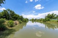 Natural water canal under a bright blue sky with white clouds Royalty Free Stock Photo