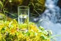 Natural water in a glass, against the background of nature and a mountain river, the concept of proper nutrition Royalty Free Stock Photo