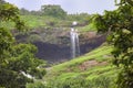 Natural waterfall surrounded by lush green vegetation