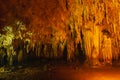 natural white stalagmite or stalactite with orange led light in dark cave in mountain