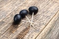 On a natural wooden background are three grape berries strung on toothpicks