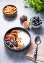 Natural yogurt with granola, berries and figs in a black bowl on a blue background with mint Royalty Free Stock Photo