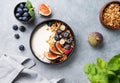 Natural yogurt with granola, berries and figs in a black bowl on a blue background with mint. Healthy and nutritious breakfast Royalty Free Stock Photo