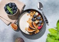 Natural yogurt with granola, berries and figs in a black bowl on a blue background with mint and shadows. Healthy and nutritious Royalty Free Stock Photo