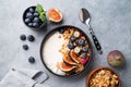 Natural yogurt with granola, berries and figs in a black bowl on a blue background with napkin. Healthy and nutritious breakfast Royalty Free Stock Photo