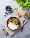 Natural yogurt with muesli, berries and figs  in a black bowl on a blue background with mint. Healthy and nutritious breakfast Royalty Free Stock Photo