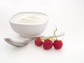 Natural yogurt, yoghurt with raspberries and spoon over white.