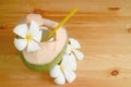 Natural young coconut juice and flesh in its shell with Plumeria flowers on a wooden table