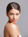 Naturally beautiful. Portrait of a beautiful young woman looking over her shoulder against a gray background. Royalty Free Stock Photo