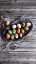 Naturally painted Easter eggs in a black clay plate on a rustic wooden background Royalty Free Stock Photo