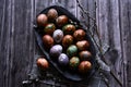 Naturally painted Easter eggs in a black clay plate on a rustic wooden background Royalty Free Stock Photo