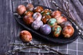 Naturally painted Easter eggs in a black clay plate on a rustic wooden background Royalty Free Stock Photo