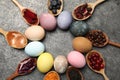 Naturally painted Easter eggs on grey table, flat lay. Turmeric, cranberries, red cabbage, onion, beetroot, blueberries, hibiscus