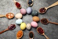 Naturally painted Easter eggs on grey table, flat lay. Turmeric, cranberries, red cabbage, onion, beetroot, blueberries, hibiscus