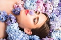 Nature beauty. Woman lying on flowers. Blossom. Makeup cosmetics and skincare. Girl with hydrangea flowers.