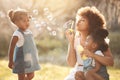 Nature, children and mother blowing bubbles in an outdoor park for playing, bonding or having fun. Happy, love and young Royalty Free Stock Photo