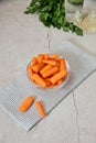 View of fresh baby peeled carrots into glass bowl on stripped napkin Royalty Free Stock Photo