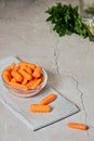 View of fresh baby peeled carrots into glass bowl on stripped napkin Royalty Free Stock Photo