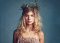 Nature has blessed her with beauty. a young woman posing with flowers in her hair against a blue background. Royalty Free Stock Photo