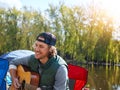 Nature inspires me musically. a young man playing his guitar while out camping. Royalty Free Stock Photo