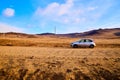 Nature landscape with car, golden grass, yellow hills and blue sky on background. Concept of world beautiful travel by Royalty Free Stock Photo