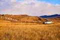 Nature landscape with car, golden grass, yellow hills and blue sky on background. Concept of world beautiful travel by Royalty Free Stock Photo