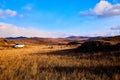 Nature landscape with car, golden grass, yellow hills and blue sky on background. Concept of world beautiful travel by Royalty Free Stock Photo