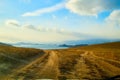 Nature landscape with golden glass, old rural road, hills and blue sky with white clouds on background in a nice day or Royalty Free Stock Photo