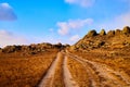 Nature landscape with golden glass, old rural road, hills and blue sky with white clouds on background in a nice day or Royalty Free Stock Photo