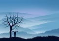 Nature landscape with mountains shrouded in fog. In the foreground the silhouettes of a person next to a tree stripped of leaves.