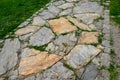 Nature paths in the park made of fine rolled trowel. irregular stone paving is overgrown with individual tufts of grass. it gives Royalty Free Stock Photo