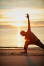 Nature is the perfect yoga partner. a man practicing the triangle pose during his yoga routine at the beach. Royalty Free Stock Photo