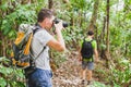 Nature photographer in tropical jungle, group of tourists hiking in the forest