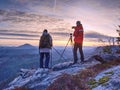 Nature photographers with big camera on tripod on summit