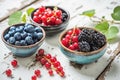 Nature's jewels: A trio of bowls showcasing blueberries, red currants, and blackberries on a simple white wooden Royalty Free Stock Photo