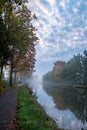 Autumnal Serenity: Canal Amidst Fall Foliage Under Cloud-Kissed Skies