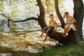 Naughty boy and girl sitting on a branch over water fishing, laughing, having fun talking Royalty Free Stock Photo